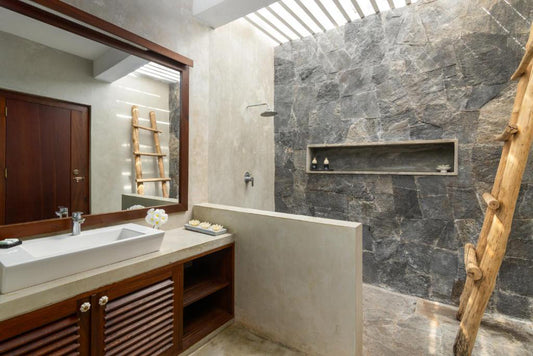 Interior view of a modern bathroom with a large walk-in shower, dark marble walls, and a wooden bench.
