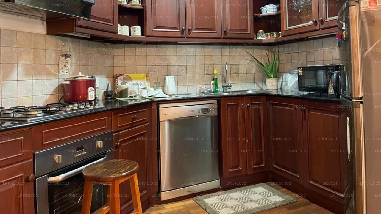Kitchen with wooden cabinets, stainless steel appliances, and a bar stool.
