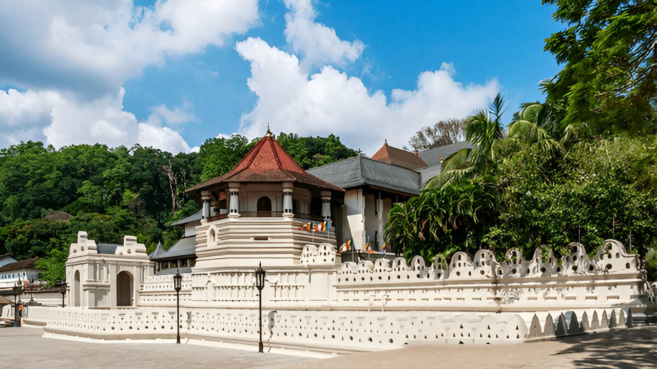 Traditional Sri Lankan temple with a red roof and white walls, surrounded by greenery.