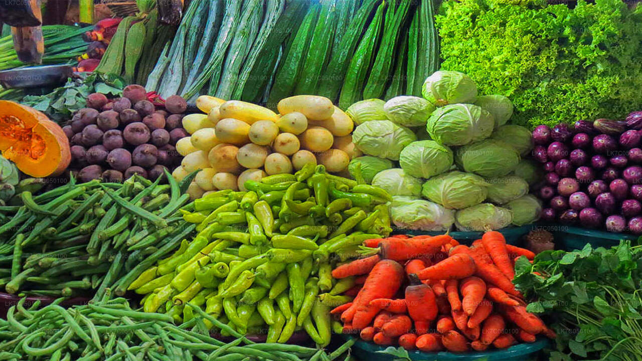 Colorful display of fresh vegetables including carrots, cabbage, beans, chilies, and potatoes at a Sri Lankan market.